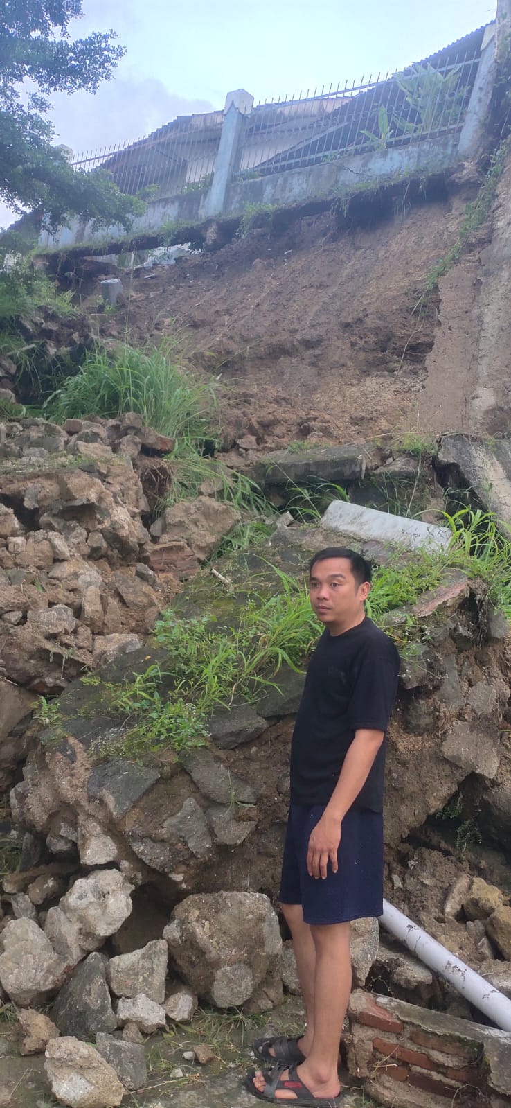 Seorang warga menunjukkan material tembok taman yang longsor di kawasan Lampu Merah Sumur Buang, Kelurahan Kaduagung Timur, Kecamatan Cibadak, Kabupaten Lebak.