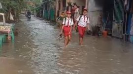 Dua orang siswa saat melintasi genangan air di Perumahan Mustika, Tigaraksa, Kabupaten Tangerang, Banten, Senin (6/5/2026)